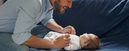 Vader ligt tegenover zijn baby op de bank en reageert op het gebrabbel van zijn 6 weken oude baby.