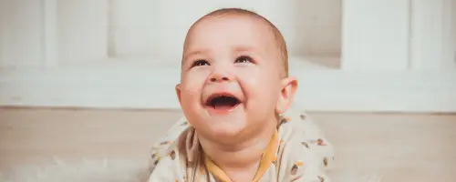 Baby ligt op haar buik tijdens tummy-time en maakt geluidjes.