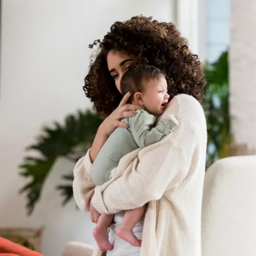 Baby huilt in de armen van haar moeder
