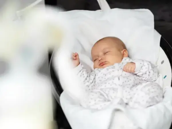 Baby ligt te slapen in babyswing