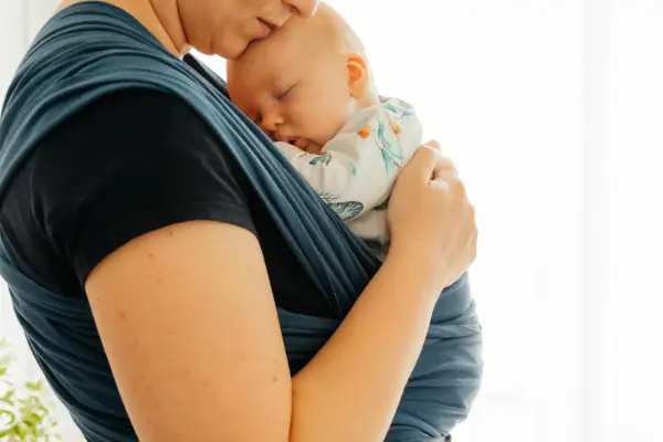 Vrouw met slapende baby in draagdoek